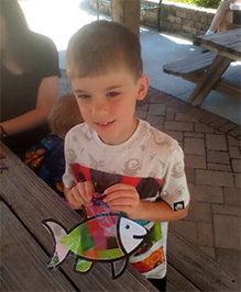 Child holding a home-made fish craft