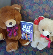 Two teddy bears sharing a book entitled 